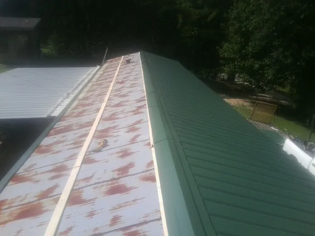 Old rusted panels beside newly installed green metal roofing — Wind Damage Roof Repair by Roofing Brothers in Beaver Meadows