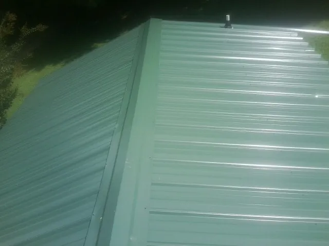 New green metal panels meeting at the ridge of a roof — Flat Roof Repair work by our crew in Beaver Meadows
