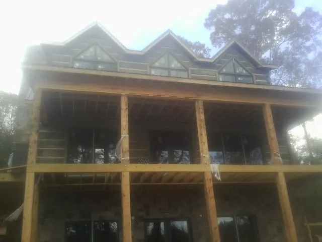 Dormers and porch framing on a large log home under construction — Roof Coating work by our crew in Beaver Meadows