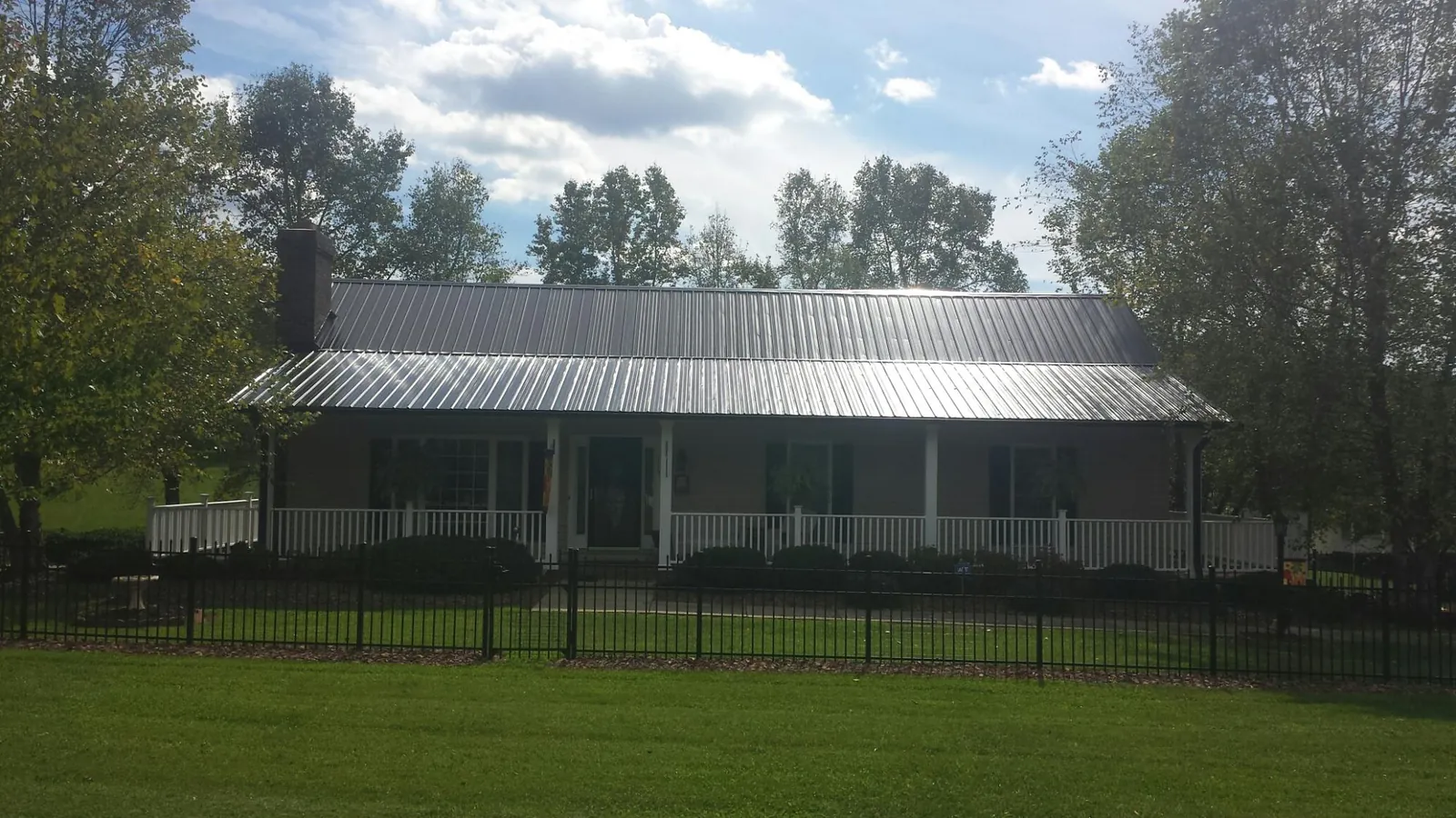 Gray metal roof on a brick ranch with a full width front porch — Gutter Guard Installation work by our crew in Beaver Meadows