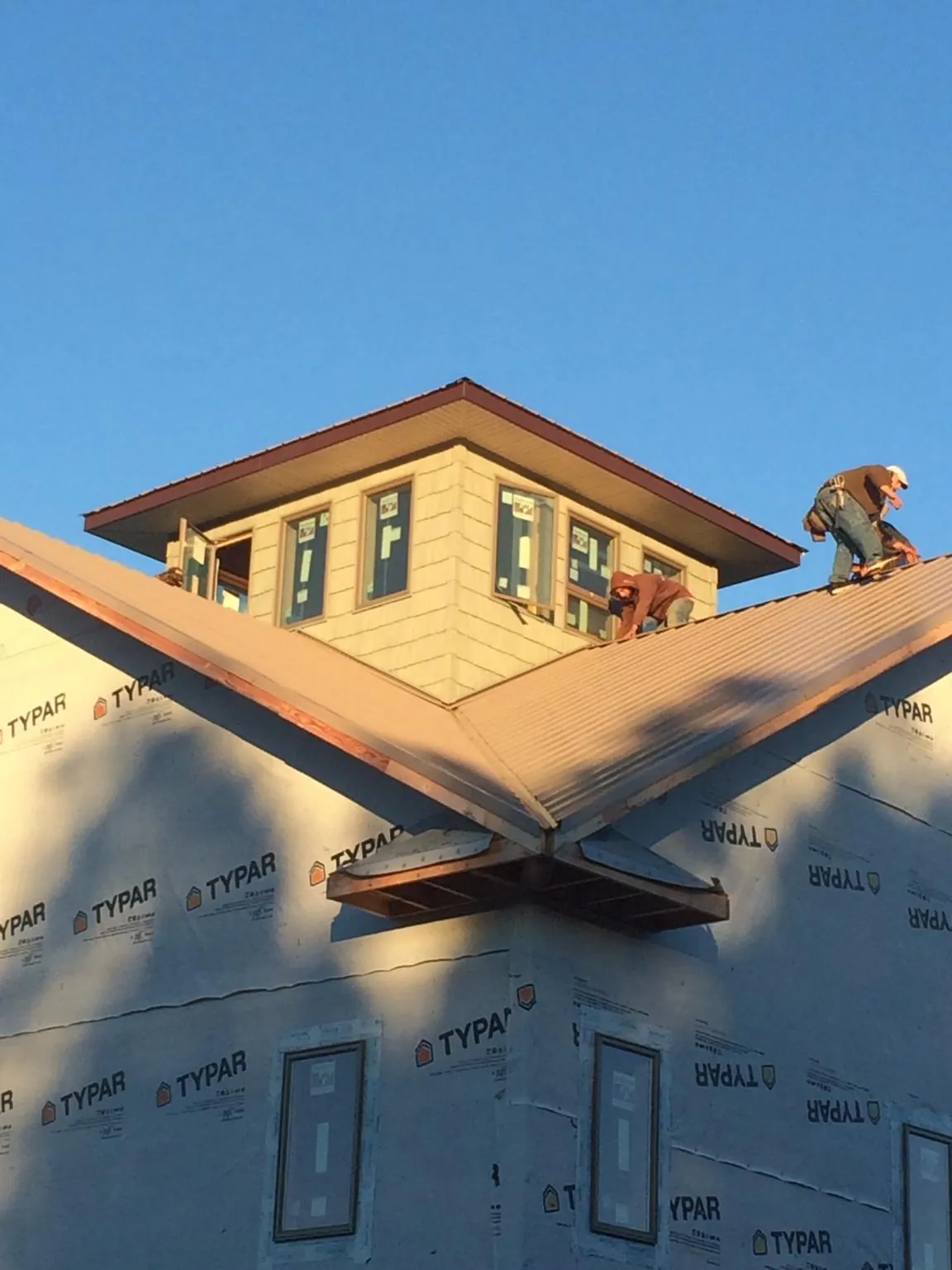 Roofers working around a rooftop cupola on a new metal roof at sunset — Roof Waterproofing in Beaver Meadows by Roofing Brothers